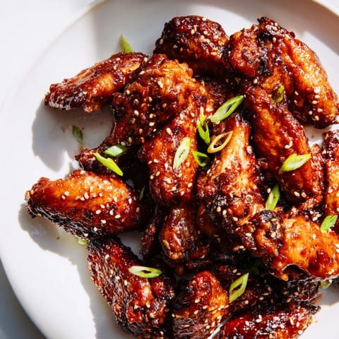 Hot Asian Sticky Wings with green onion and sesame seed garnish on a platter.
