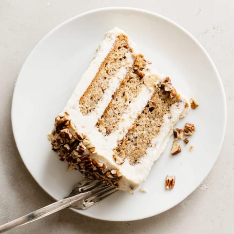 Decadent slice of Hummingbird Cake with pineapple and banana filling, served on a dessert plate.