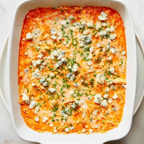 Baked Buffalo Chicken Dip in a dish topped with bubbly golden mozzarella, ready for dipping.