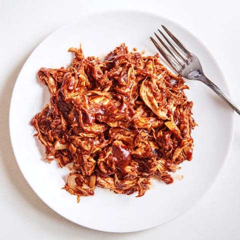 Tender, slow-cooked BBQ Pulled Chicken piled high on a toasted bun with tangy slaw.