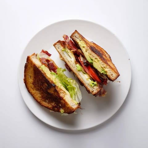 Melted cheddar oozes from buttery bread, stacked with crisp bacon, fresh tomato, and ripe avocado.