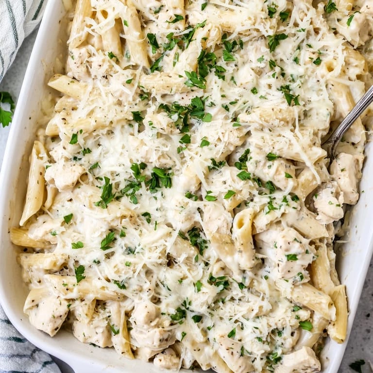 Steam rises from a freshly baked Chicken Alfredo Bake, served family-style with a simple green salad.