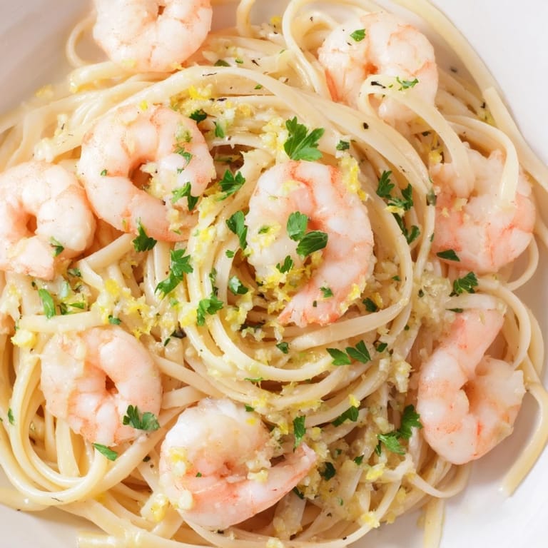 Plump, pink shrimp nestle in a silky lemon-garlic butter sauce coating al dente linguine, garnished with parsley and lemon zest.