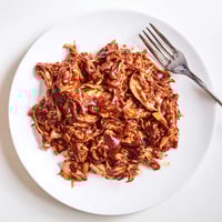 Tender, slow-cooked BBQ Pulled Chicken piled high on a toasted bun with tangy slaw.