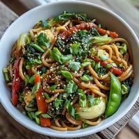 Steaming ginger-sauced Shirataki Noodle Bowl with crisp bok choy and red bell peppers in a skillet.