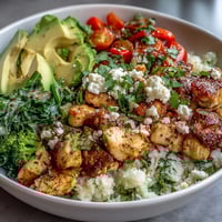 Colorful cauliflower rice bowl loaded with grilled chicken, avocado, and fresh veggies for a low-carb meal.