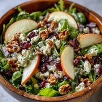 Fresh Mixed Greens and Apple Bowl with crisp apple slices, crunchy walnuts, and creamy goat cheese, drizzled with tangy cider vinaigrette.