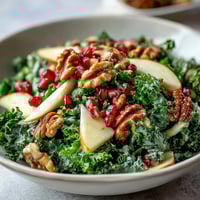 Freshly massaged kale tossed with crisp apple slices, juicy pomegranate seeds, and chopped walnuts, all lightly coated in a sweet and tangy apple cider vinaigrette.