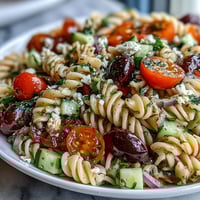 Fresh summer pasta salad with Italian dressing, colorful vegetables, and mozzarella, perfect for picnics and potlucks.